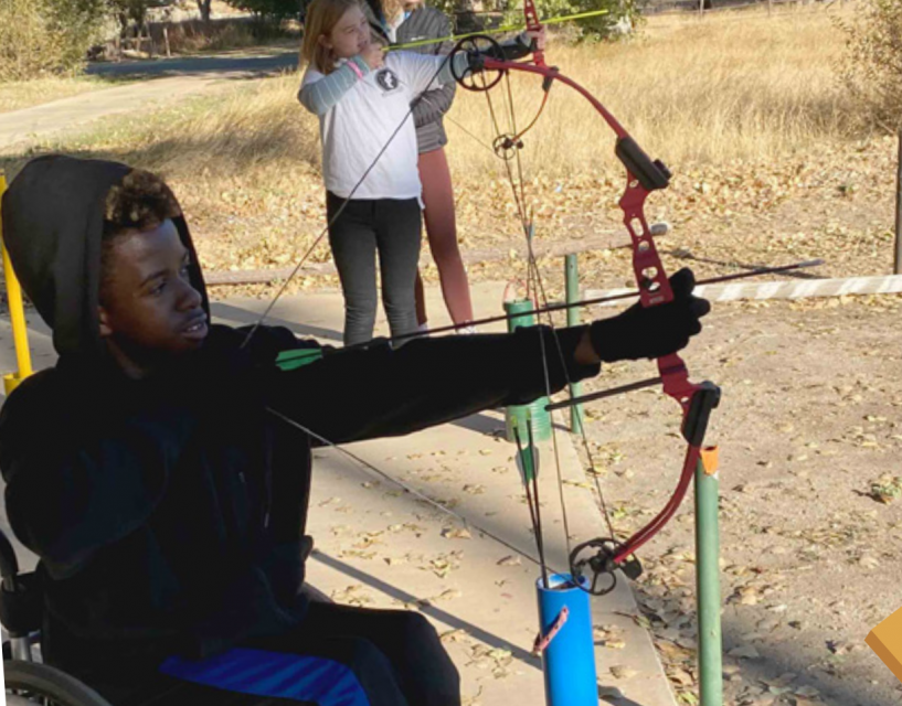 James using a bow and arrow at the archery range. 