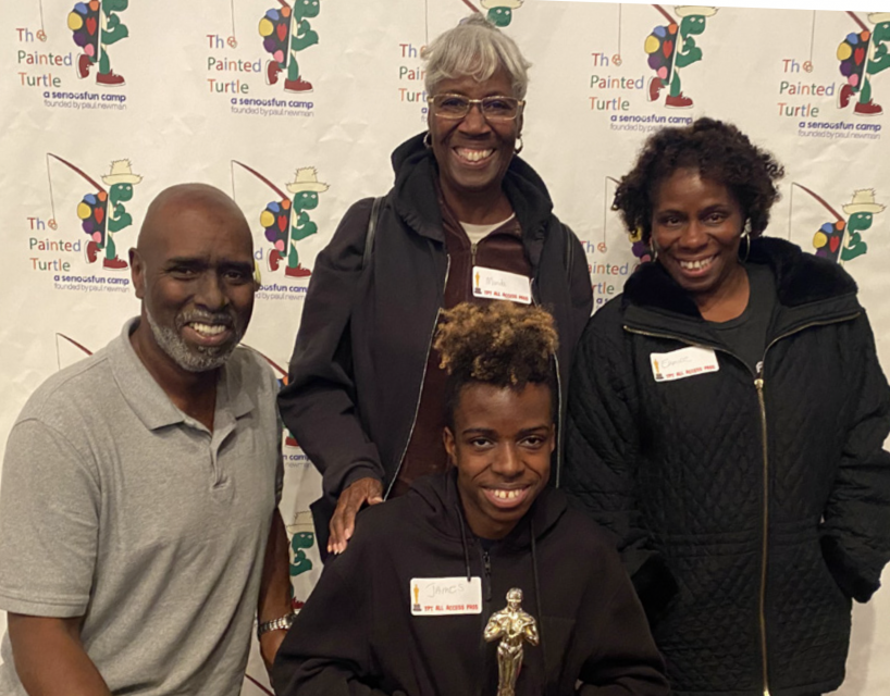 James and three of his family members pose for a photo holding a trophy at Camp