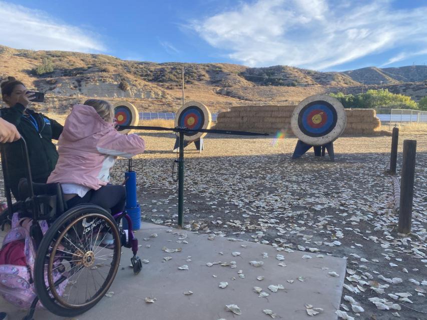 Camper in wheelchair at archery shooting towards target