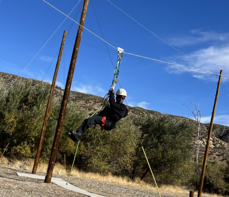 James taking the zipline down from the top of the ropes course