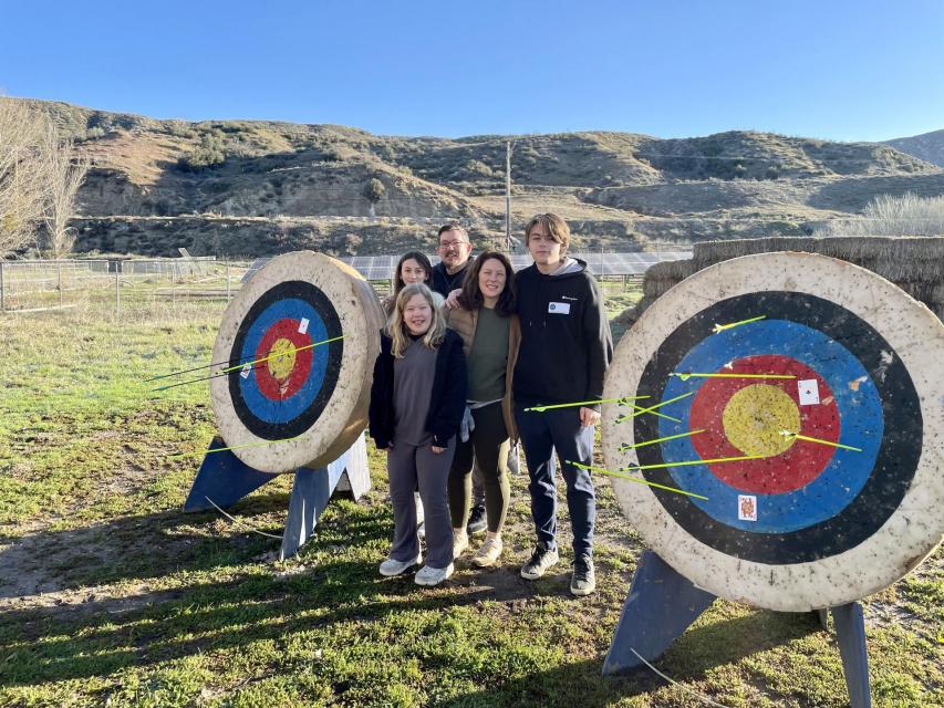 Family of four standing in front of tow round archery targets. 