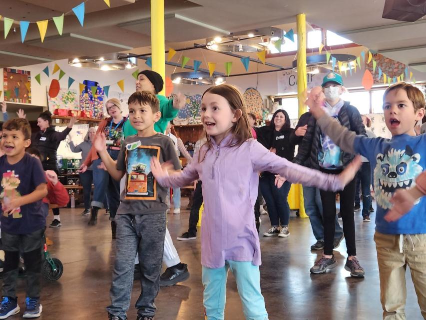 Young girl dancing with joy in the dining hall with a group of people dancing around her
