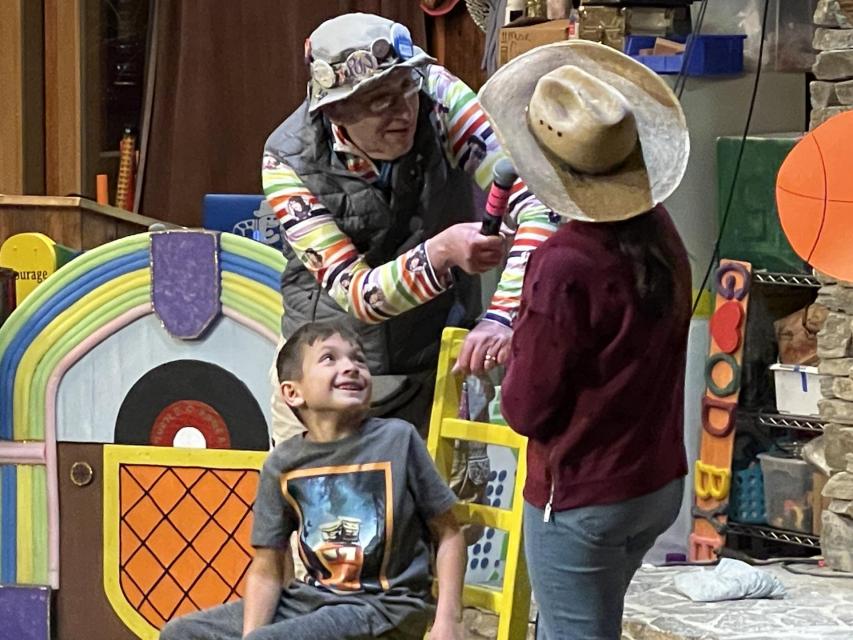 Volunteer and two campers performing a magic trick at Stage Night. 