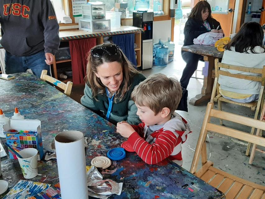 Volunteer and camper working on a craft project in Arts and Crafts.