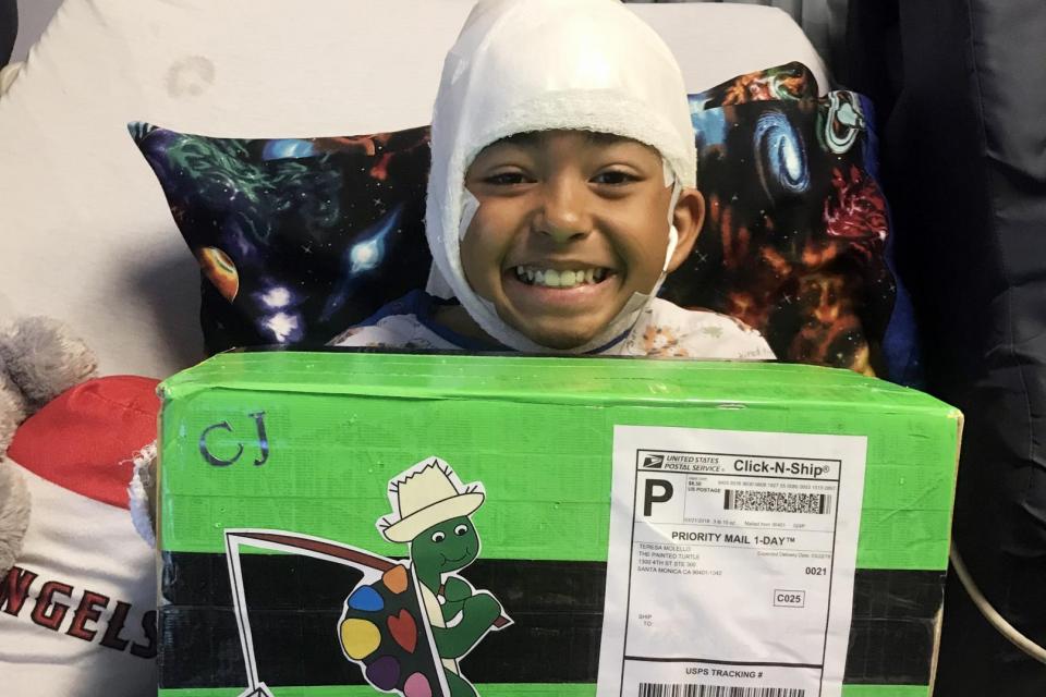 A camper smiling while holding a Turtle-Gram care package. 