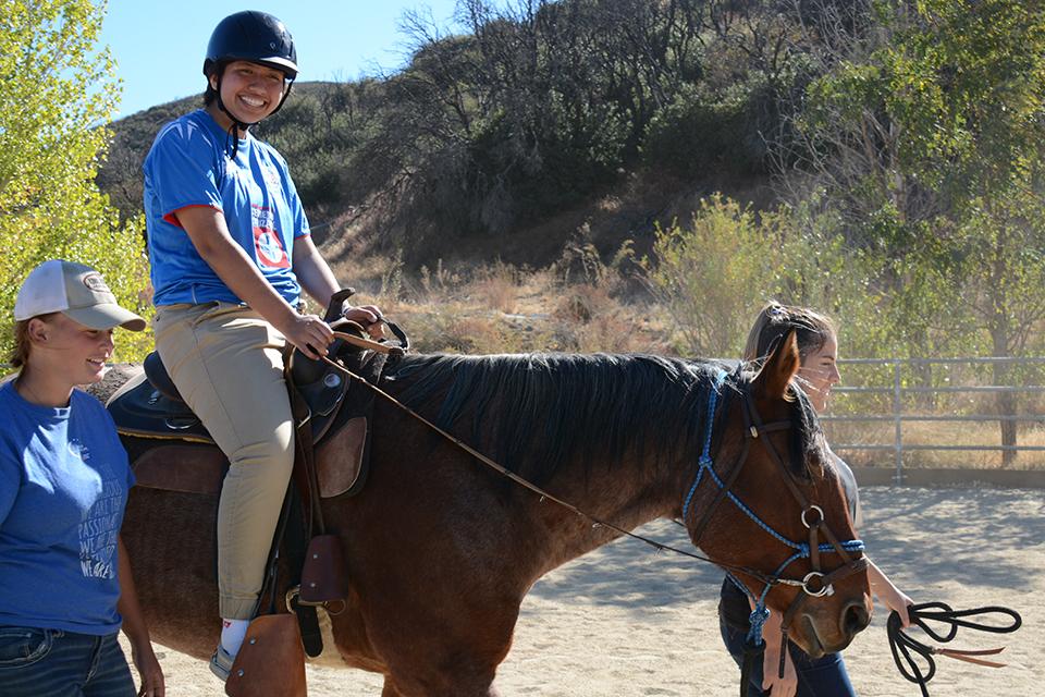 Boy, smiling, riding horse.