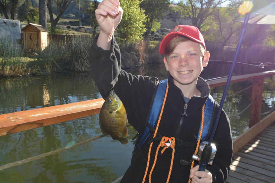 Boy holding freshly caught fish by the lake
